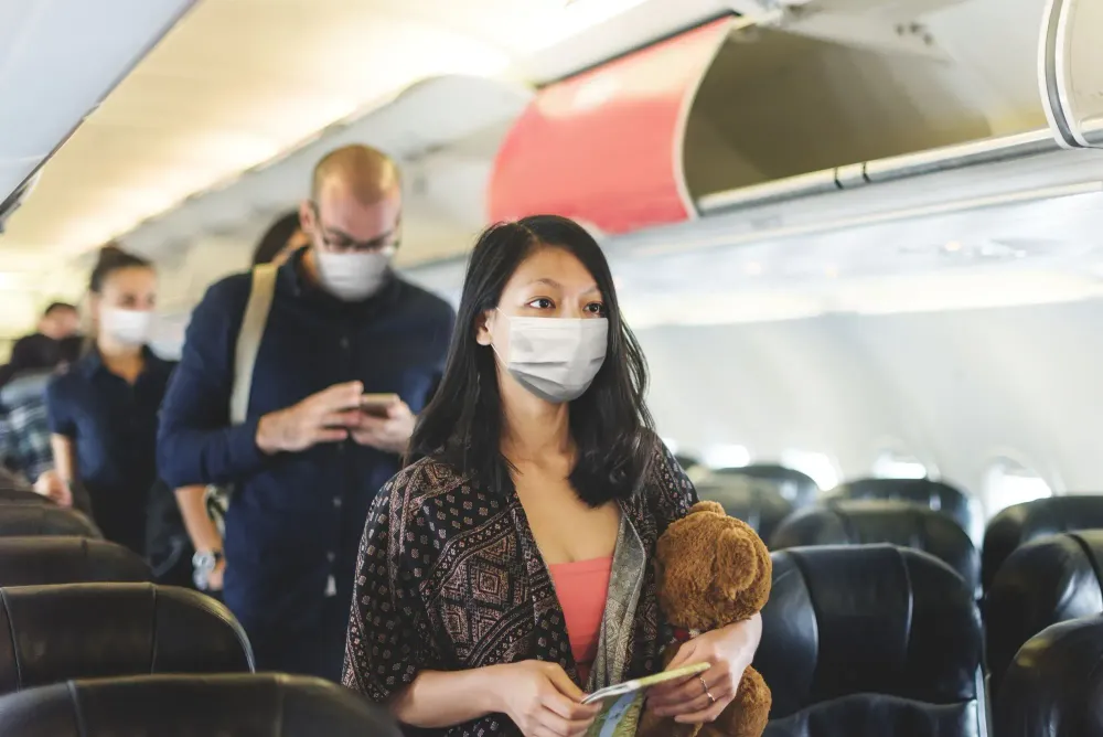 A line of people looking for their seats on the plane and wearing protective face masks